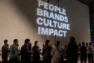 Crowd watching a projection that reads People, Brands, Culture, Impact